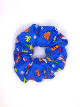 Load image into Gallery viewer, A cotton scrunchie featuring Hawaiian local childhood favorites such as pineapple, poke bowl, spam musubi, milk tea, and shave ice on a blue background.
