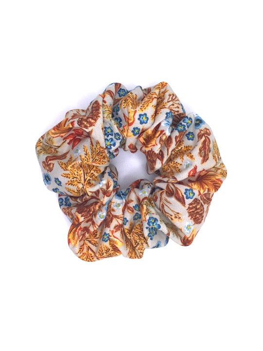 Autumn-themed cotton scrunchie with red, orange, and brown foliage leaves and blue flowers, perfect for adding a seasonal touch to any hairstyle.