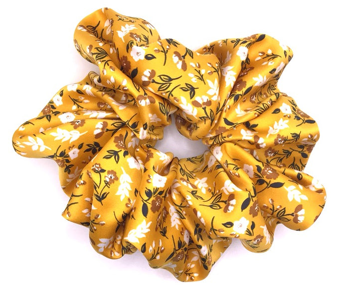 A yellow XXL satin scrunchie with a floral design featuring small white and yellow flowers with vines.