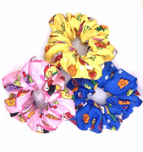 Load image into Gallery viewer, Three cotton scrunchies featuring Hawaiian local childhood favorites such as pineapple, poke bowl, spam musubi, milk tea, and shave ice on a yellow, blue, or pink background.
