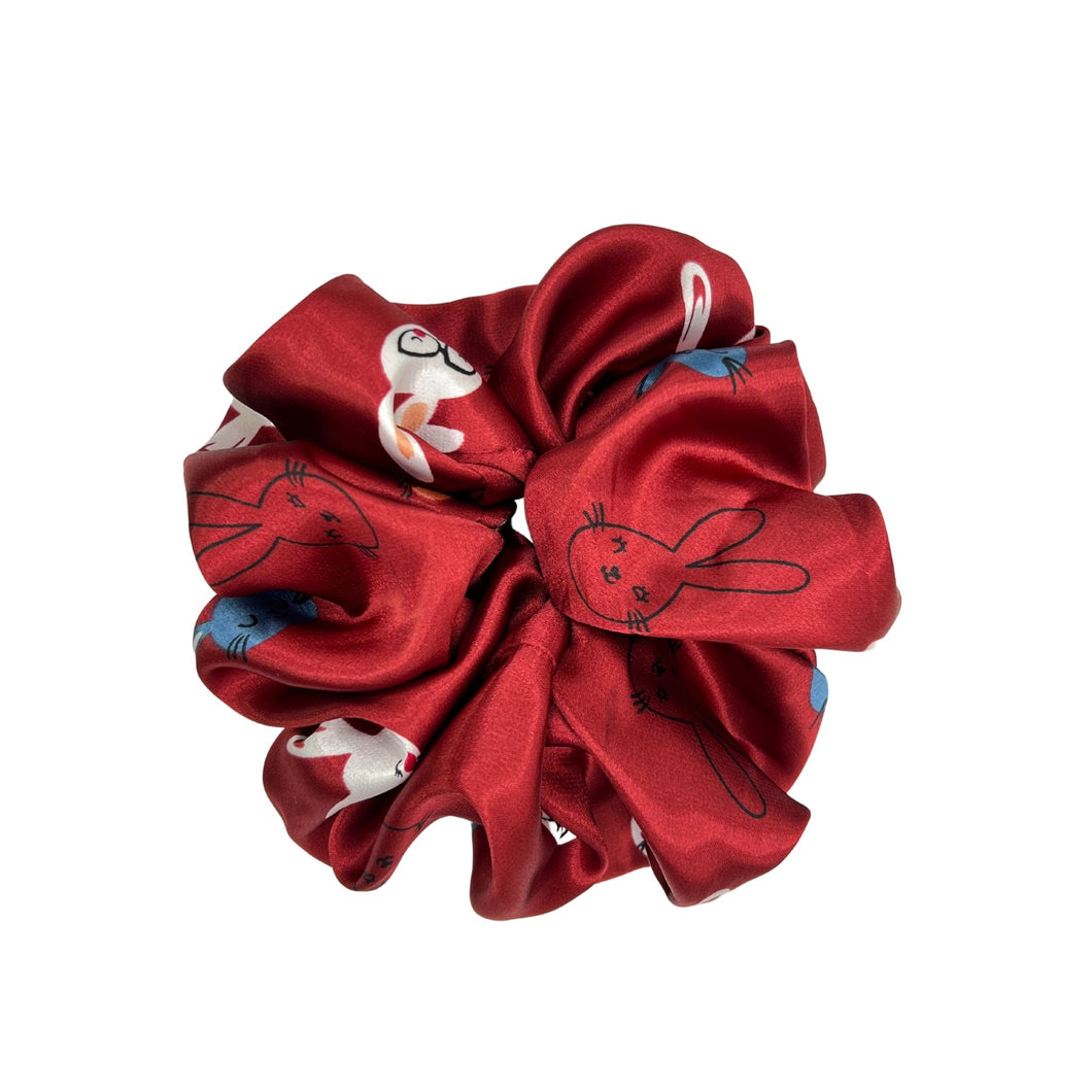Satiny crimson scrunchie with three different cartoon rabbit head designs: outline, white with glasses, and one in blue.