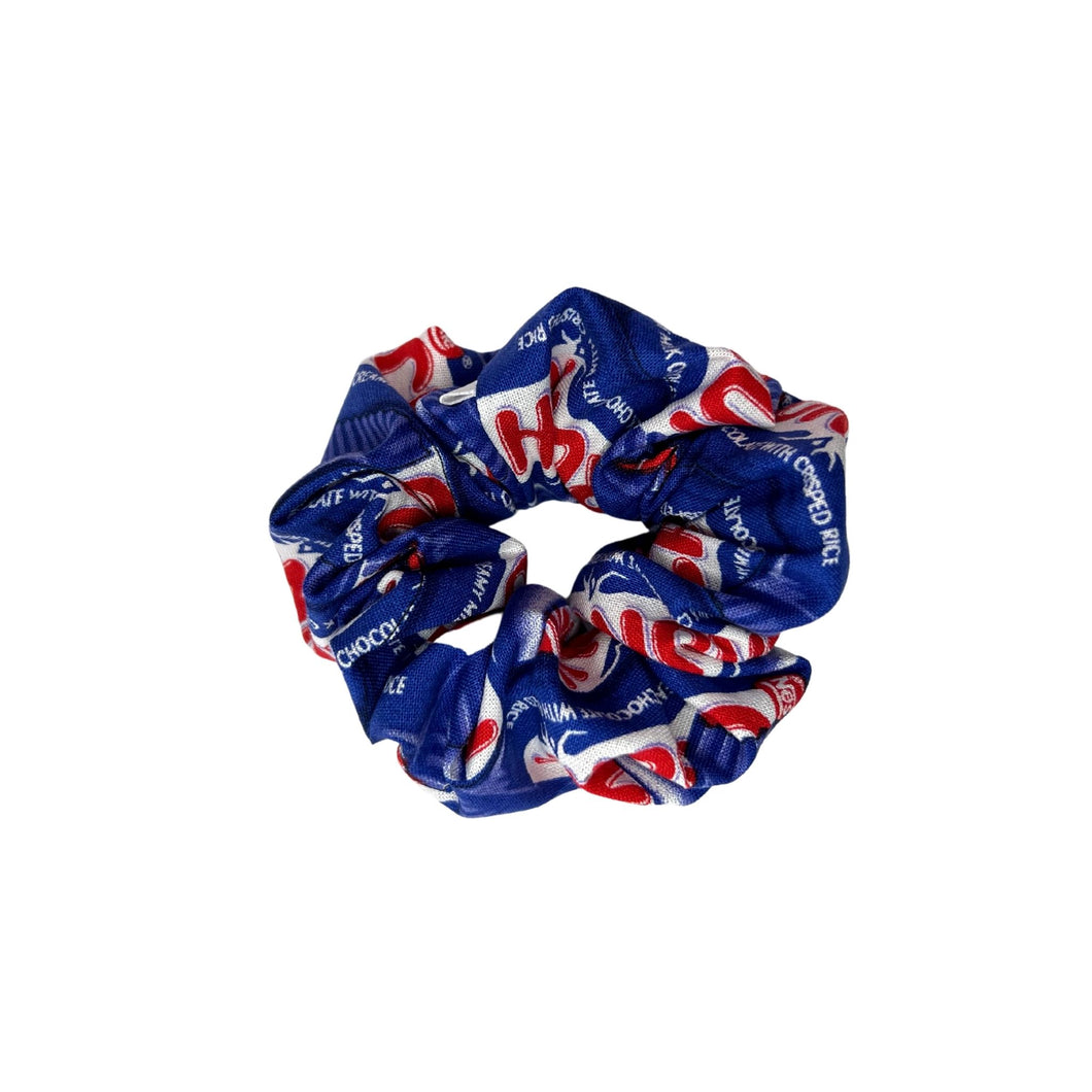Cotton scrunchie in playful Crunch candy bar print, featuring shades of blue, white, and red.