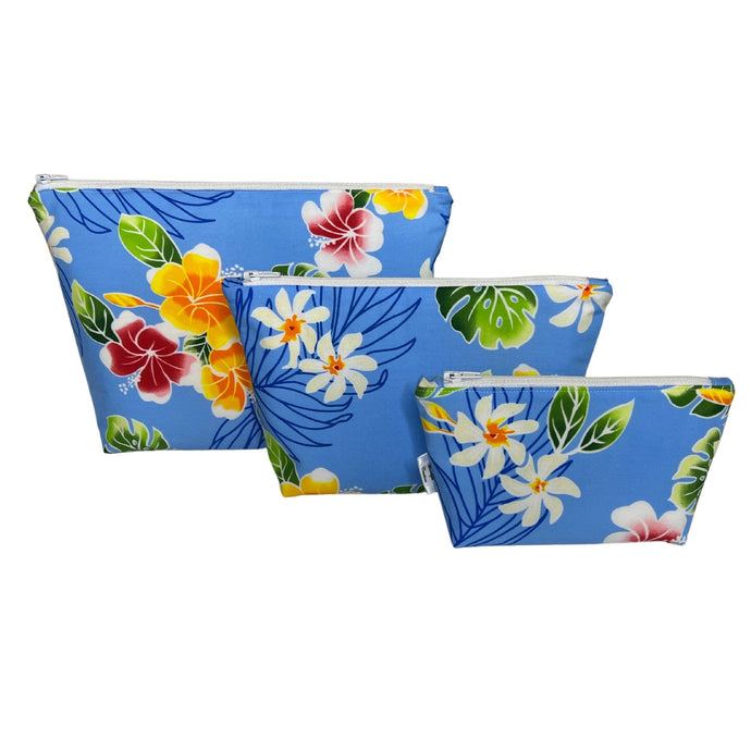 Three makeup bags made of tropical blue fabric with yellow and red hibiscus, monstera leaves, and white pualani flower. Includes large, medium, and small sizes.