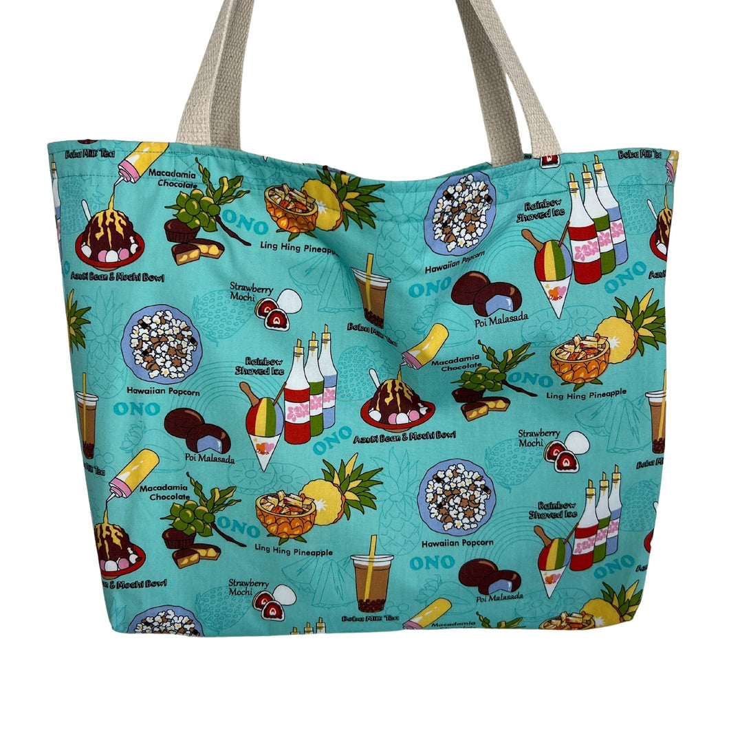 A large teal tote bag with colorful illustrations of Hawaiian local favorites including boba tea, shave ice, strawberry mochi, poi malasada, ling hing pineapple, and Hawaiian popcorn.