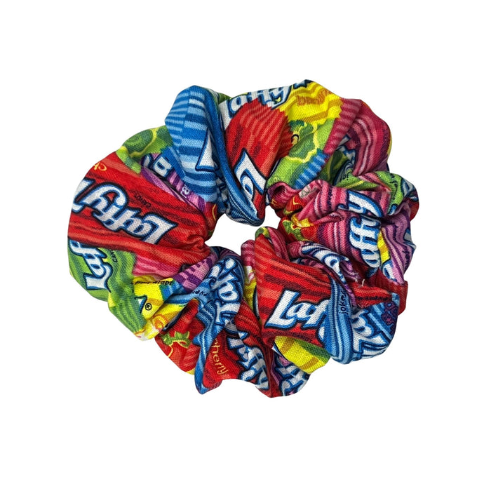 Cotton scrunchie in vibrant Laffy Taffy candy print, featuring a colorful assortment of pink, purple, blue, and yellow stripes. Soft and durable fabric, gentle on hair with strong, stretchy elastic for a comfortable hold. Perfect accessory for any occasion, from casual outings to special events.